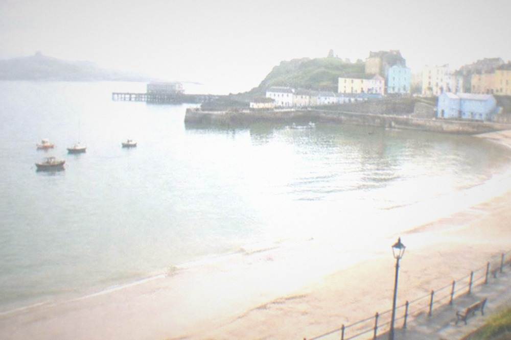 A calm sandy bay in early morning light with an empty promenade