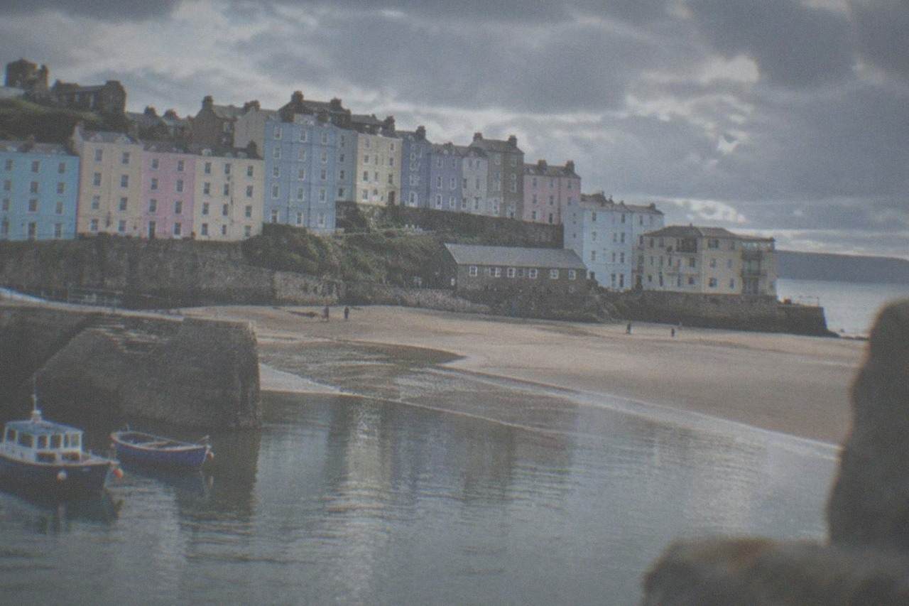 Pastel coloured Georgian houses rising above a sandy beach beside a small harbour