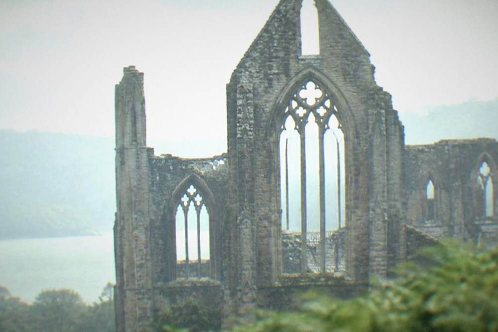 Tall empty gothic window frames of a ruined abbey church against the sky