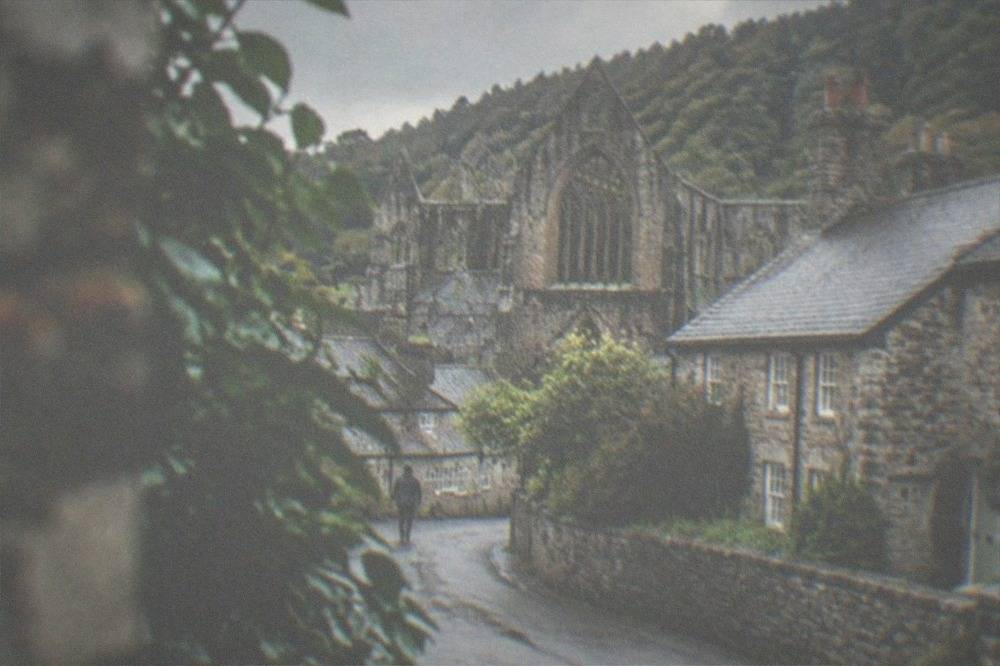 A quiet village street with stone cottages beside a wooded hillside