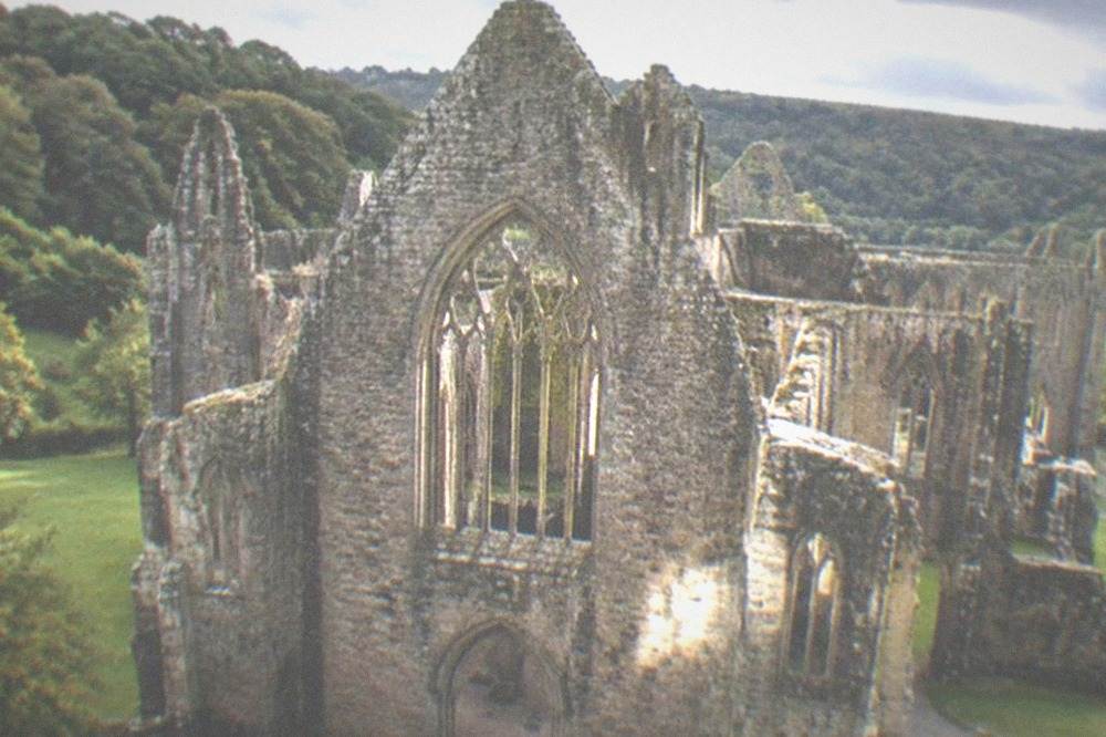 Afternoon light falling on the stone west front of a ruined abbey