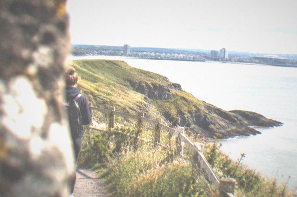 A coastal footpath winding along a grassy clifftop above the sea