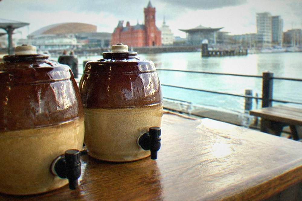 Two capped cask ale jugs resting on a wooden bar top