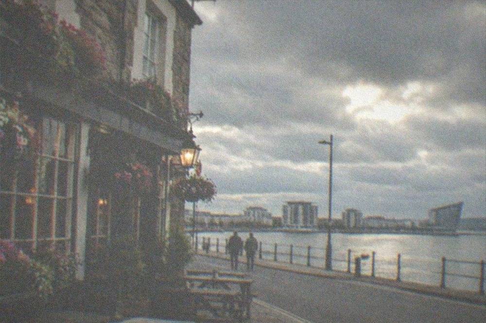A cosy neighbourhood pub front with flower boxes on a quiet evening street