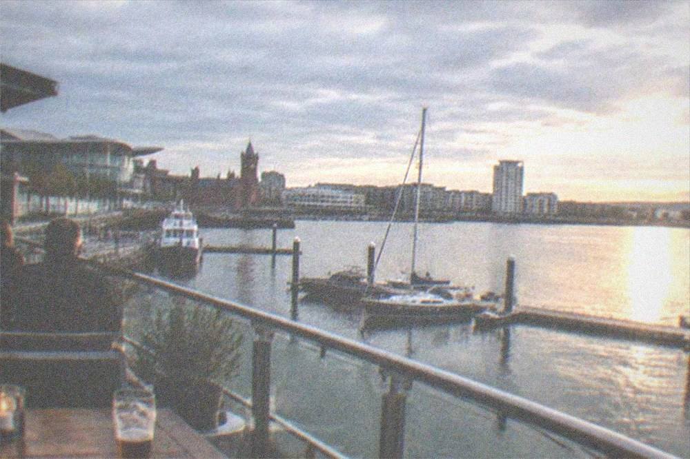 A waterfront bar terrace overlooking a dock at dusk with boats moored nearby