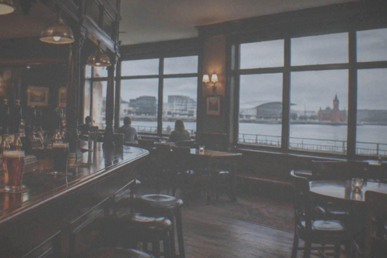 A traditional pub interior with wooden bar, brass taps and warm lamplight