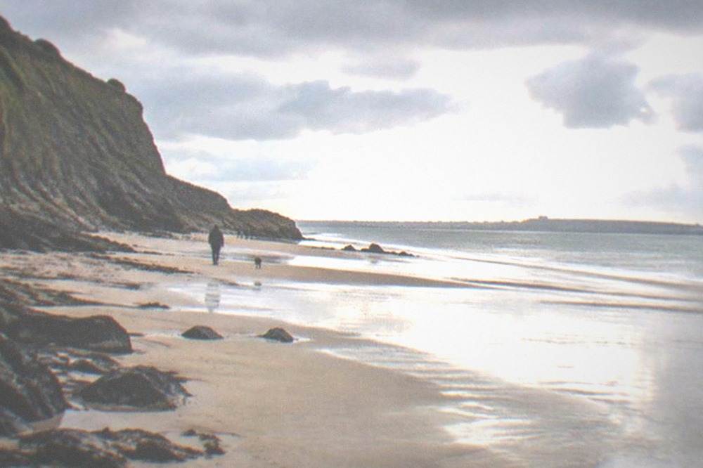 Wide sandy beach at low tide beneath cliffs on the south Wales coast