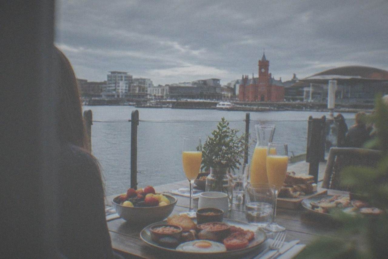 A table set for a Cardiff bottomless brunch with glasses, fruit and a full Welsh plate