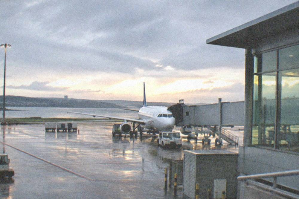 A small airport terminal building with a plane at the gate in evening light