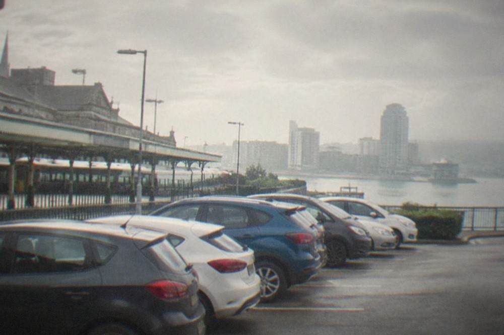 A row of hire cars parked in a bay beside a railway station in Cardiff