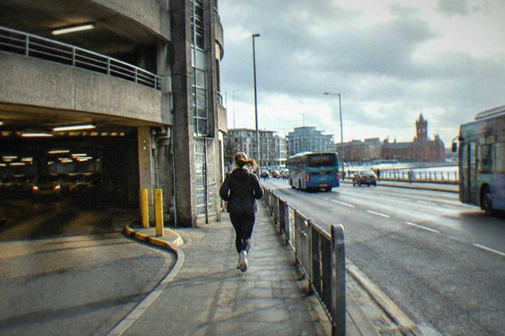 A multi-storey car park entrance on a busy Cardiff street with buses passing