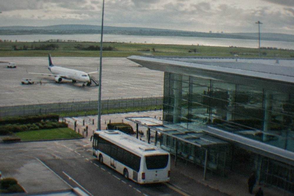 A bus waiting at an airport kerbside stand outside a terminal building