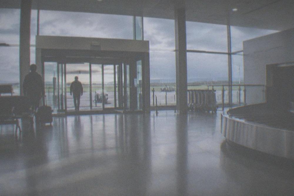 A quiet airport arrivals hall with a small baggage reclaim area and exit doors