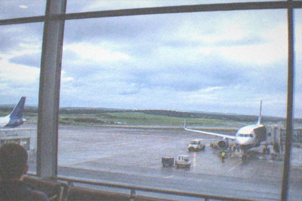 A bright airport departure lounge with rows of seats and windows looking onto the apron