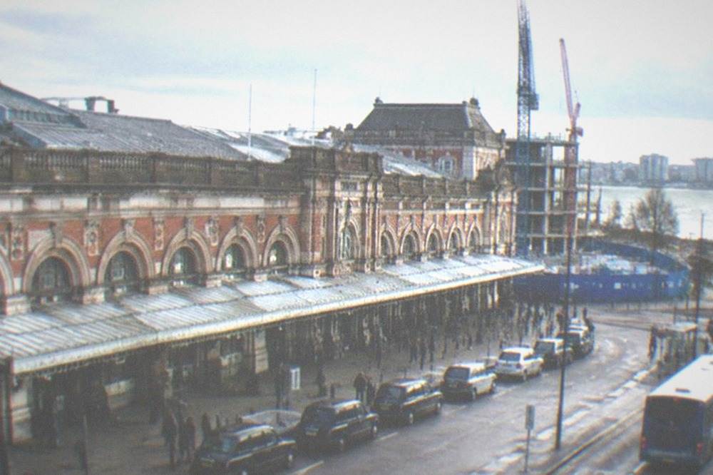 Construction hoarding and cranes beside a railway station entrance