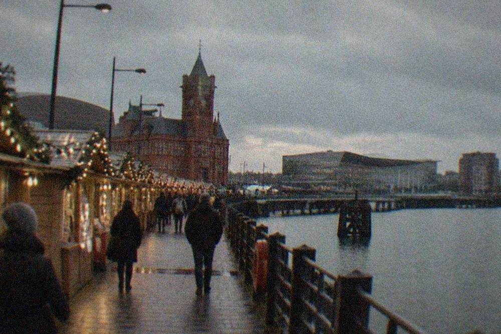 Festive wooden market stalls with string lights along a city street in the evening