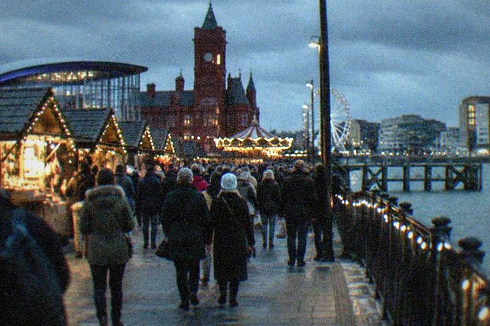 Crowds walking along a decorated city street with wooden market stalls
