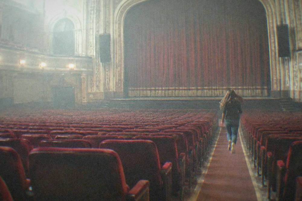 A grand auditorium with red seating and a stage framed by high proscenium arches