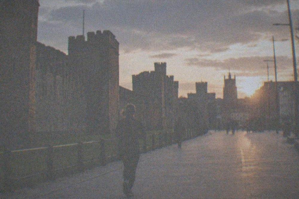 The city centre at dusk with the castle walls on one side and a wide pedestrian street ahead