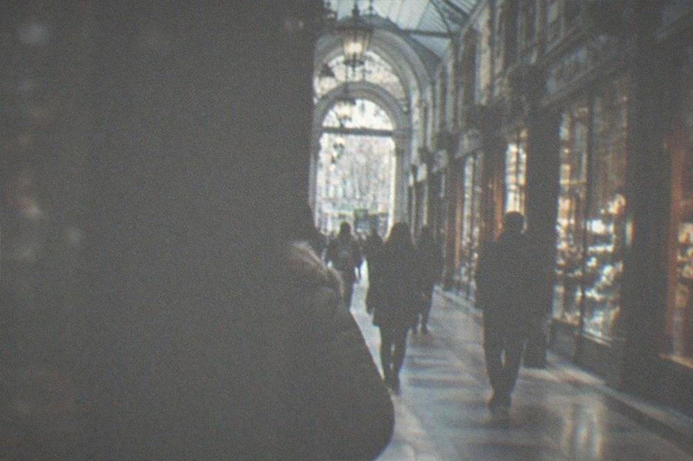Shoppers walking through a Victorian shopping arcade with lit shopfronts