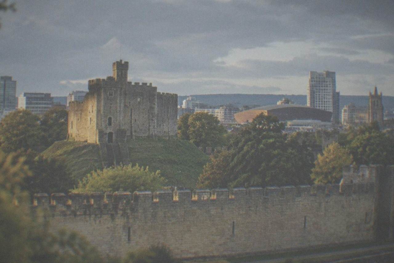 Cardiff Castle keep with the city skyline behind it on a bright day