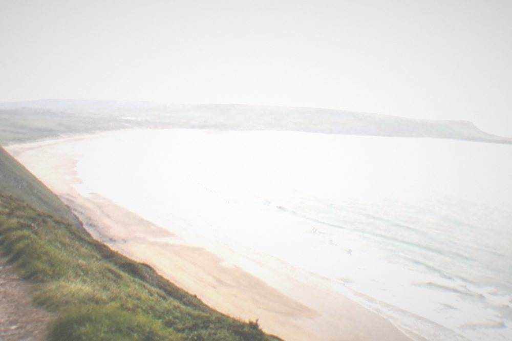 Wide sandy curve of Rhossili Bay seen from the cliff path