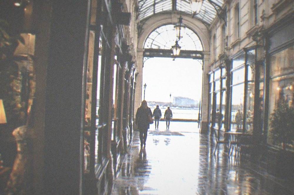 Covered Victorian arcade interior with shops lit on a wet afternoon