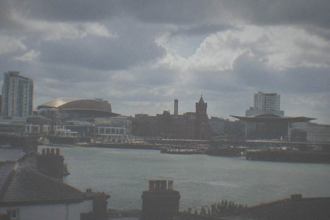 Cardiff city skyline under a partly cloudy sky above the rooftops