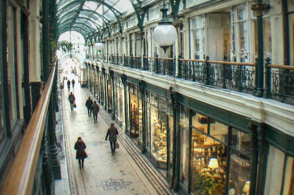Covered Victorian arcade interior with shopfronts and a glass roof