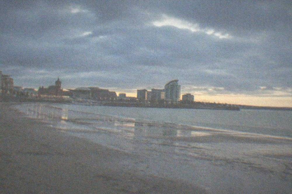 Wide sandy beach at low tide with a promenade behind