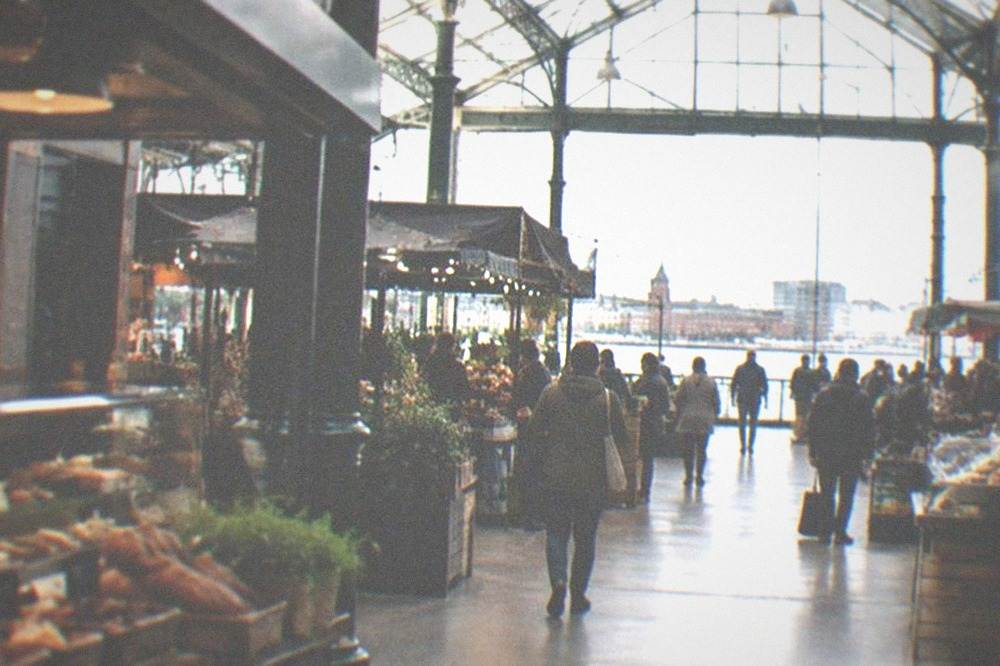 Busy indoor market hall with food stalls and a glass roof