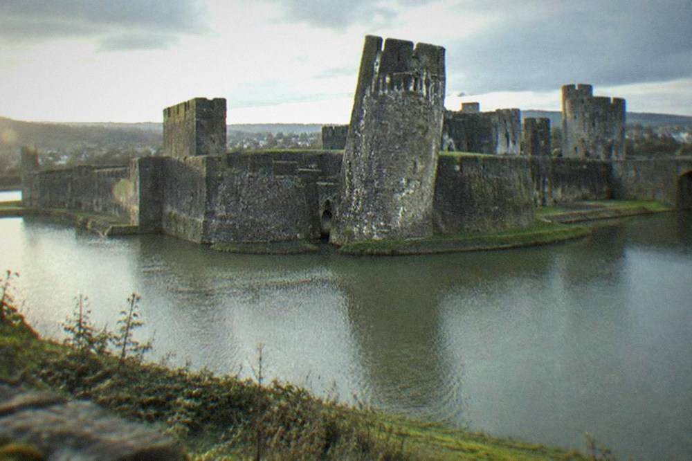 Leaning tower of Caerphilly Castle with stone walls and grassy moat