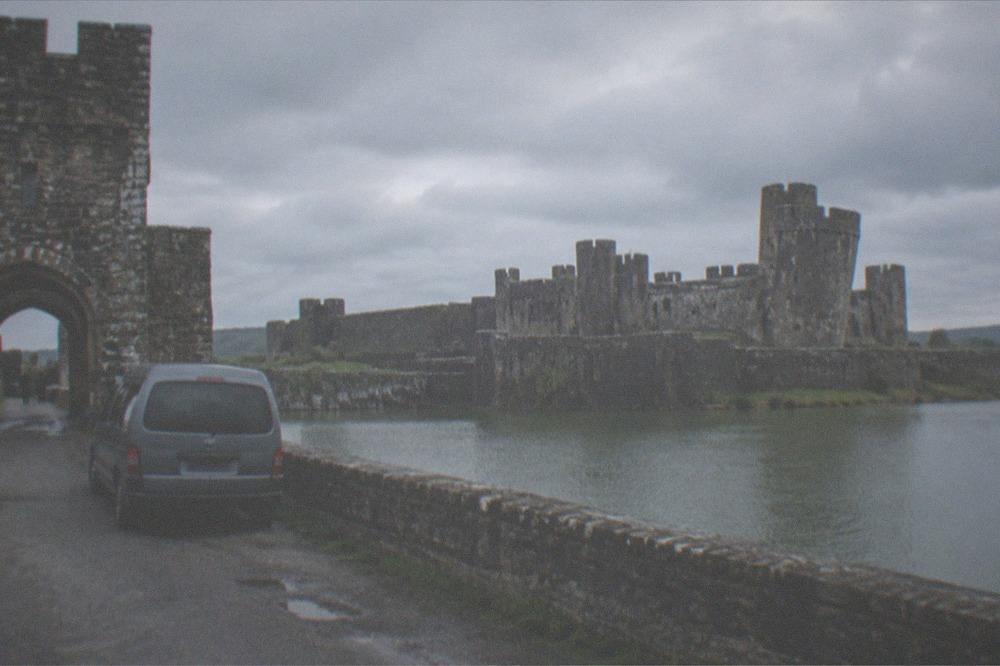 Minivan parked on a country lane beside an ancient stone castle gate