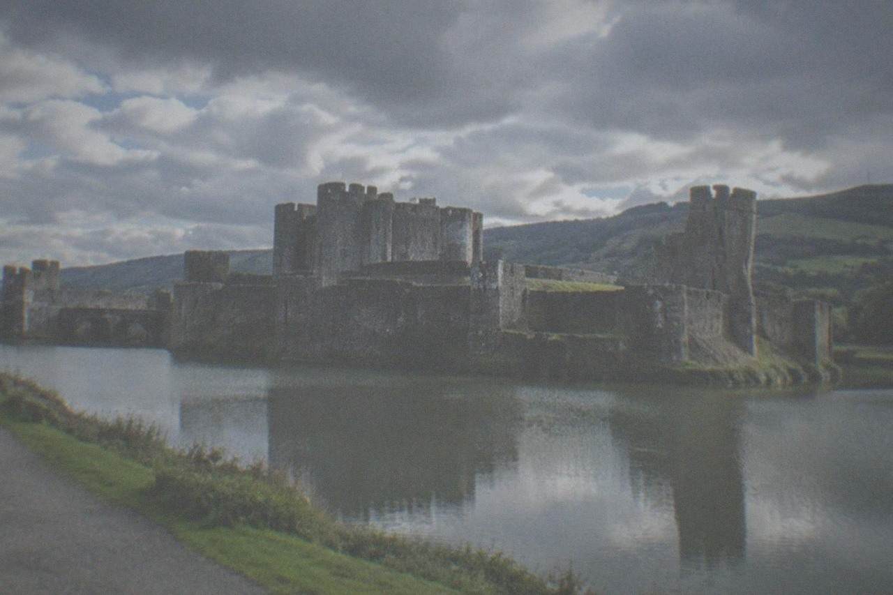 View of Caerphilly Castle across its moat with green hills behind