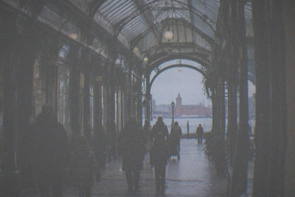 Families strolling through a covered Victorian shopping arcade with ironwork and glass roof