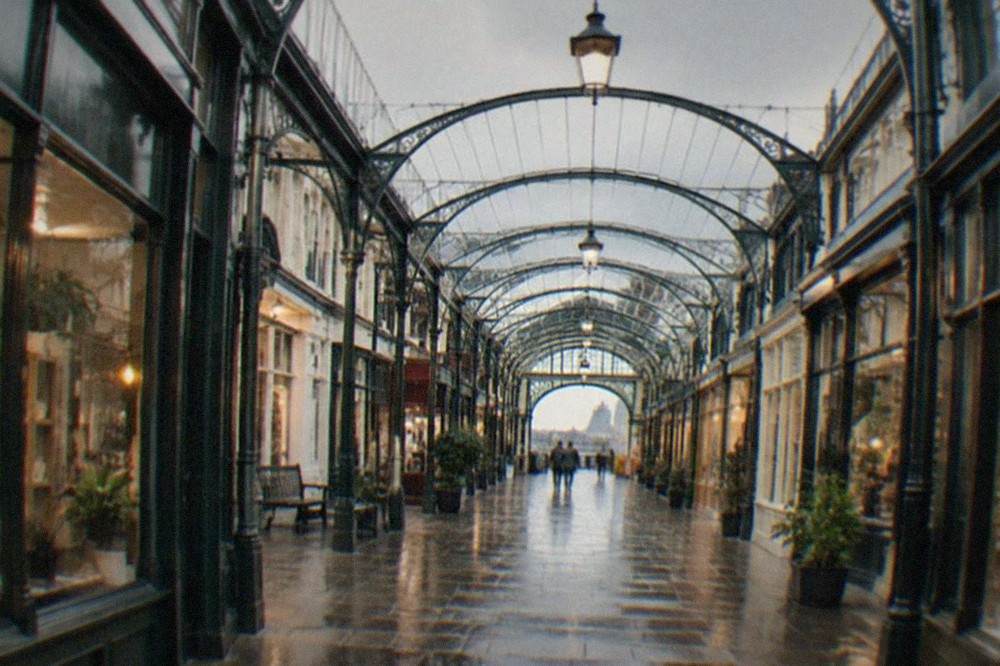 A Victorian shopping arcade interior with ironwork arches and small independent shopfronts