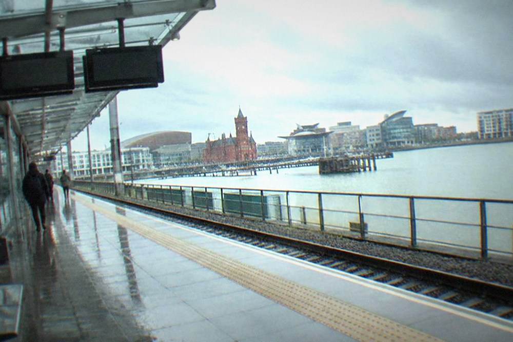 Modern train platform with a shelter and departure screens under a glass roof