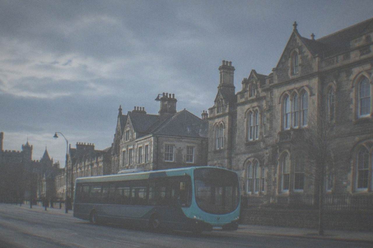 A Cardiff bus passing Victorian stone buildings on a wide city street