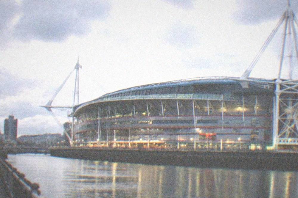Lit Principality Stadium exterior seen from Westgate Street at night