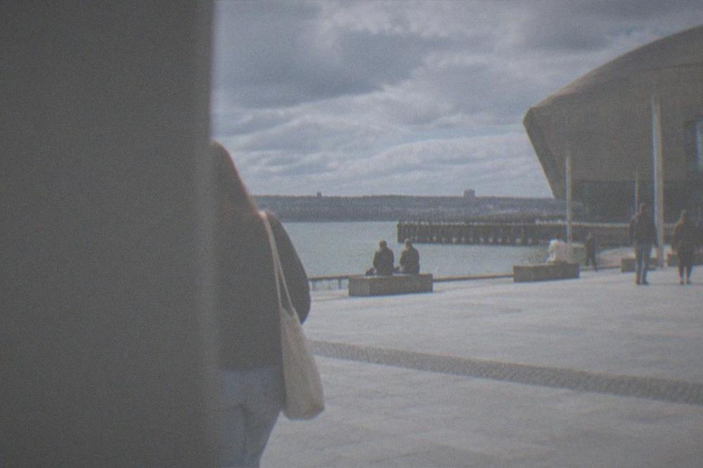 A wide waterfront plaza beside a modern arts centre building