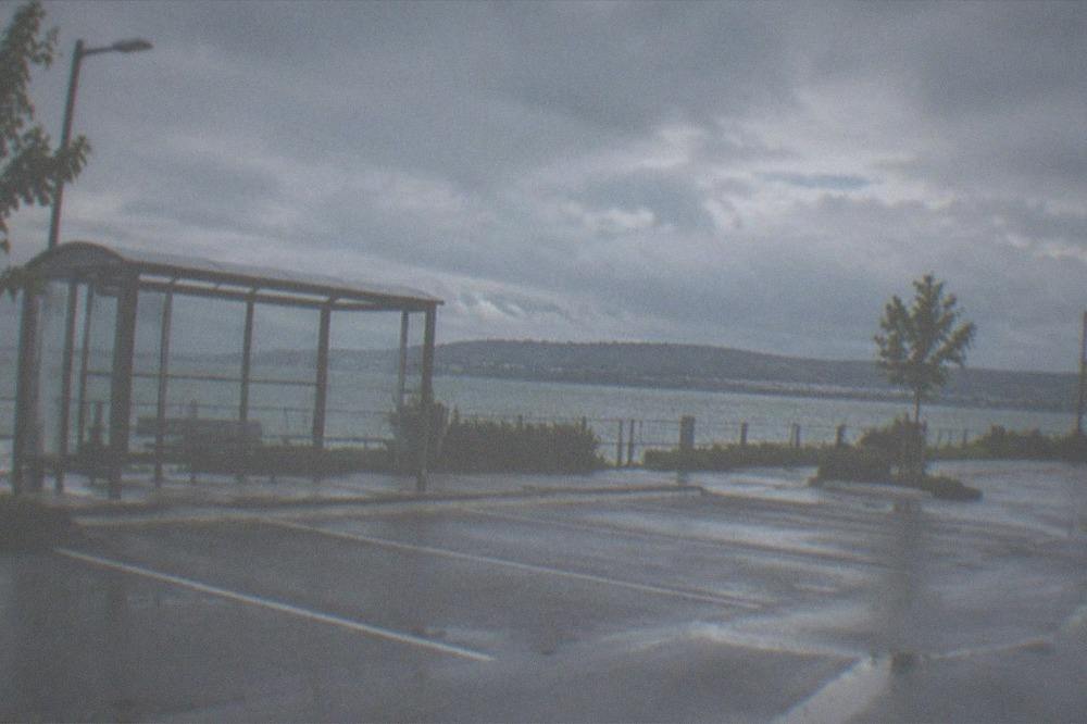 Empty park and ride surface car park with a bus shelter and distant hills