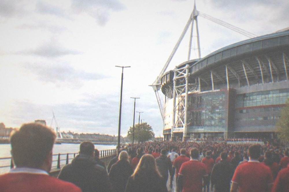 Crowds in red shirts filling a city street outside a stadium before a match