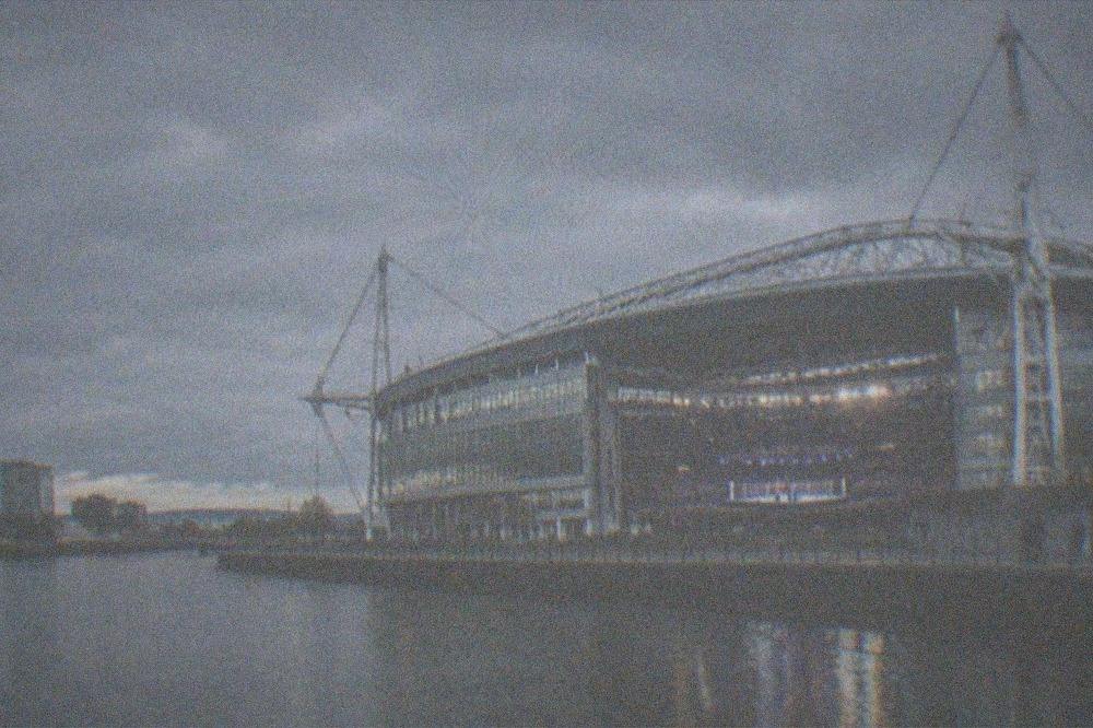 A stadium bowl lit up at night with a boxing ring set up on the pitch