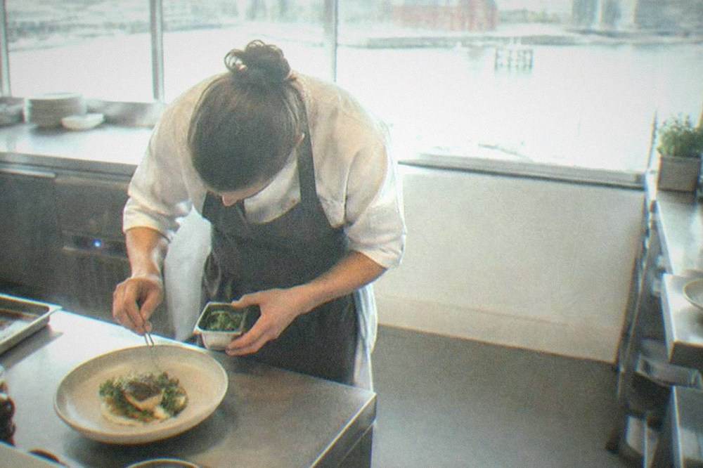 A chef plating a seasonal dish on a restaurant counter in Cardiff