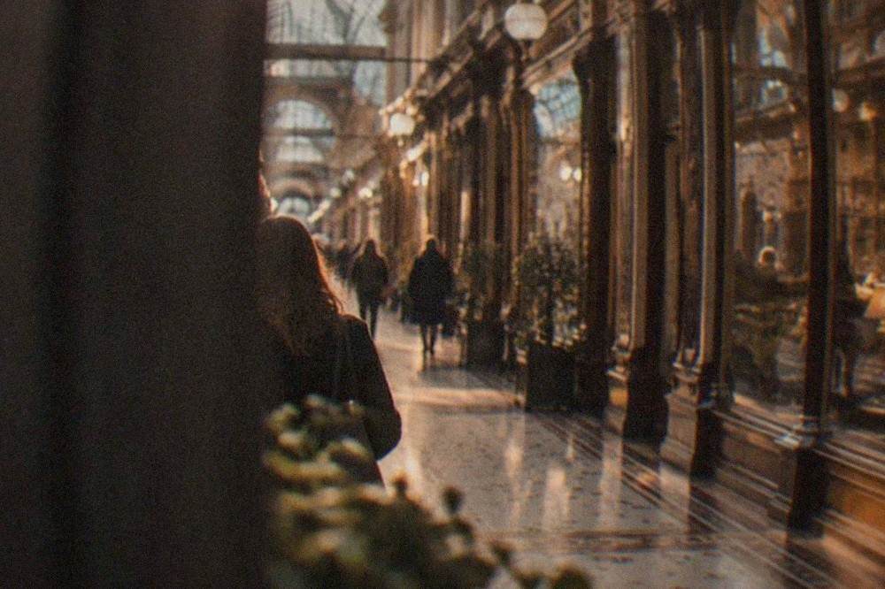 A busy indoor shopping arcade with ornate Victorian shopfronts and hanging signs