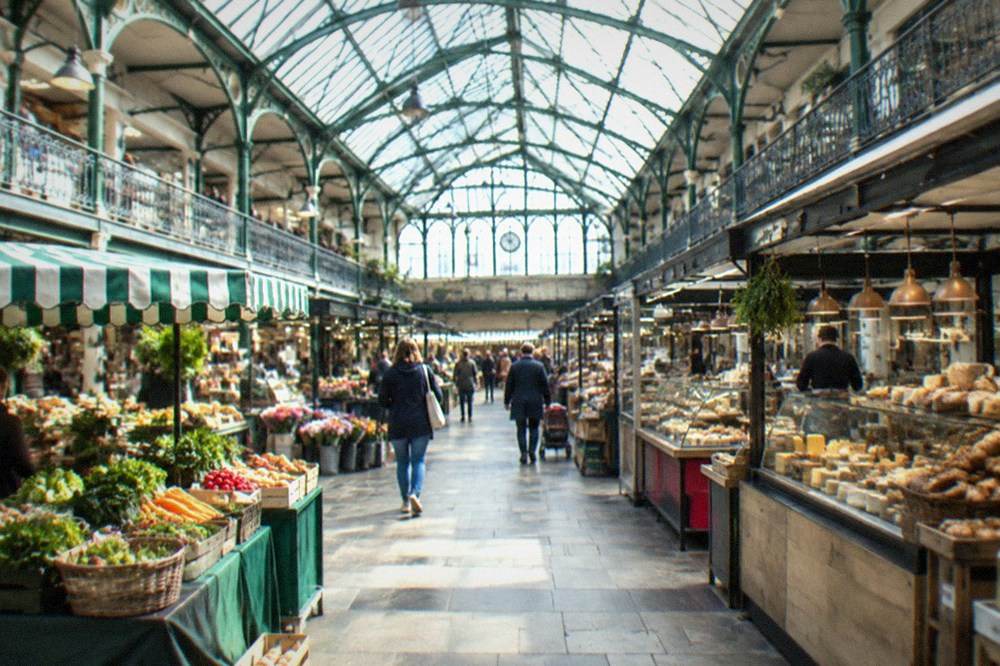 A market hall interior with food stalls under a high glass roof