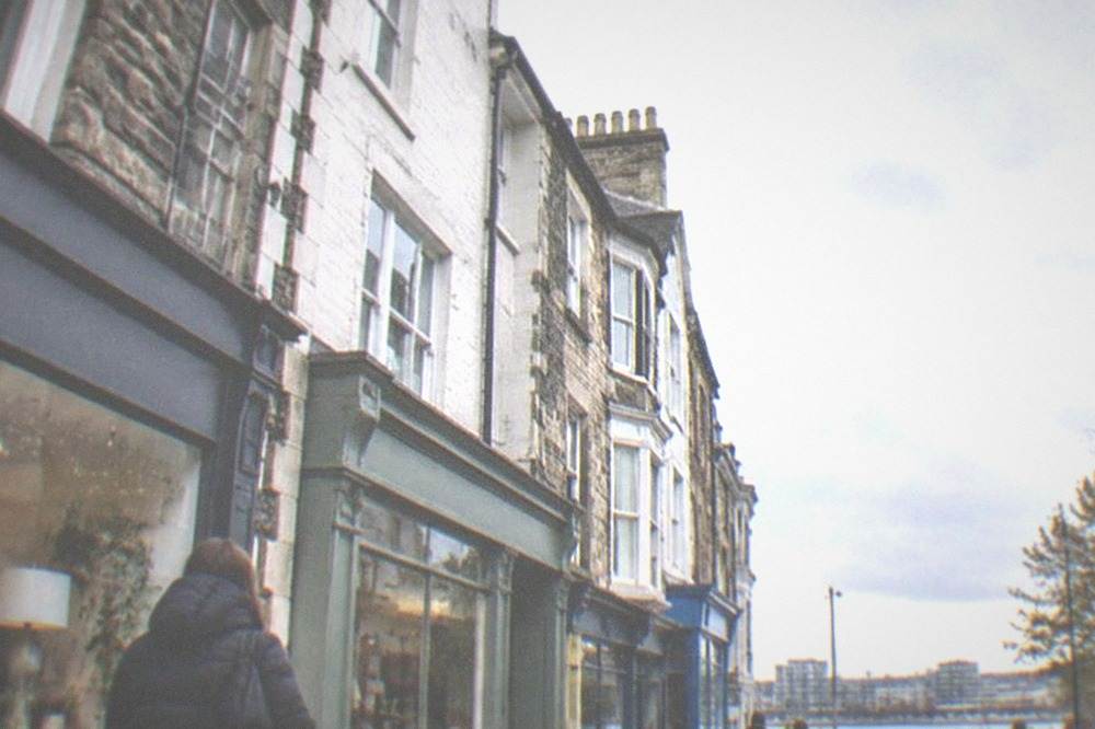 An independent shopping street with small shopfronts and people browsing on the pavement