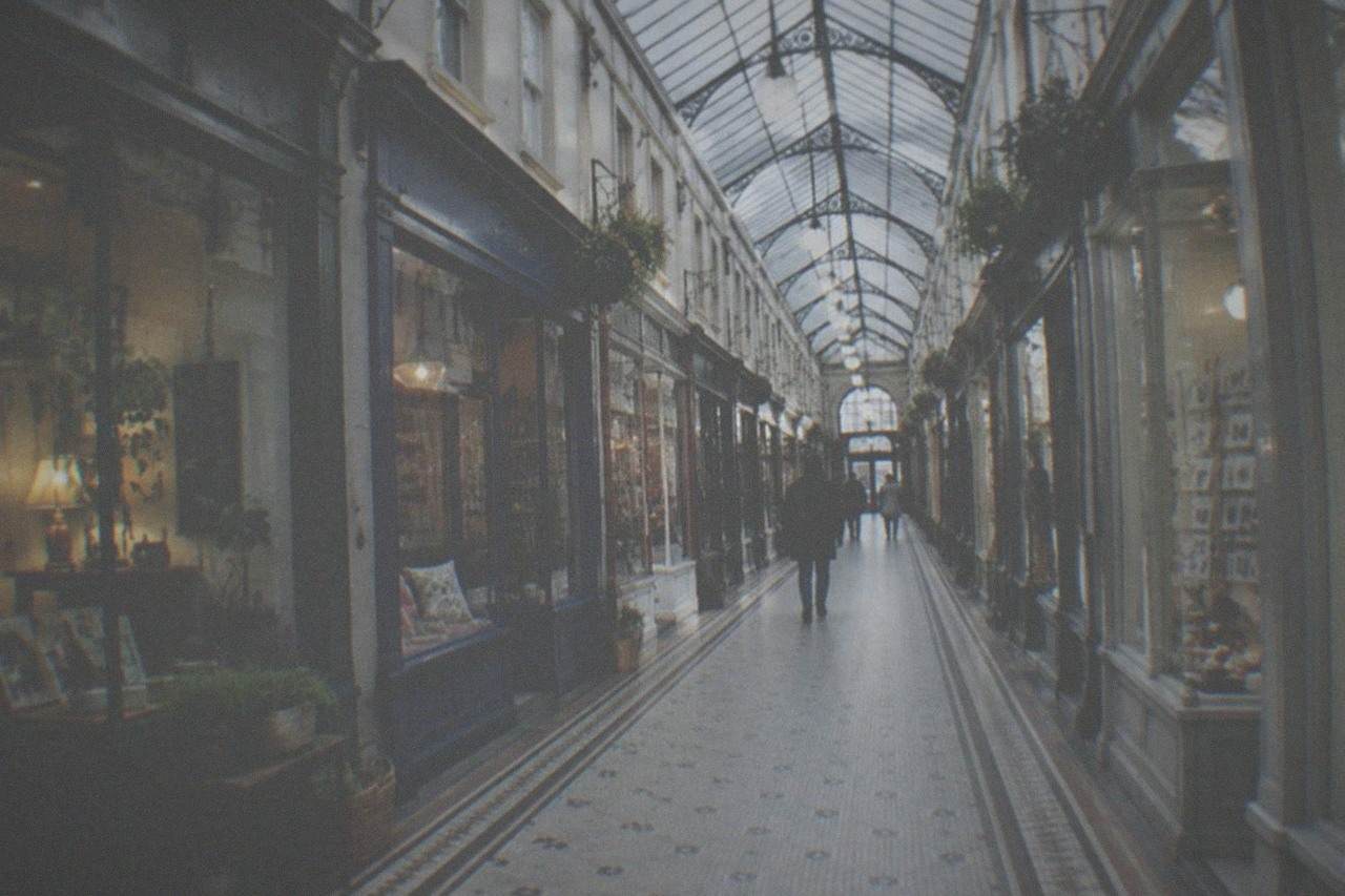 A covered Victorian shopping arcade in Cardiff with small independent shopfronts under a glass roof