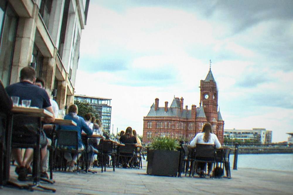 Row of Cardiff restaurant tables outside a city centre building with people dining in daylight