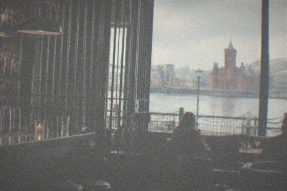 Dimly lit cocktail bar interior with prison style metal details and bottles on shelves